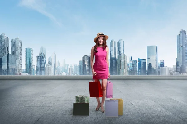 Woman with hat holding shopping bags — Stock Photo, Image