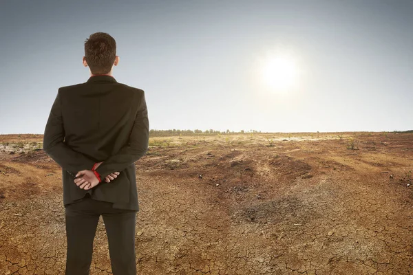 Бізнесмен спостерігає на сухій землі і заході сонця — стокове фото