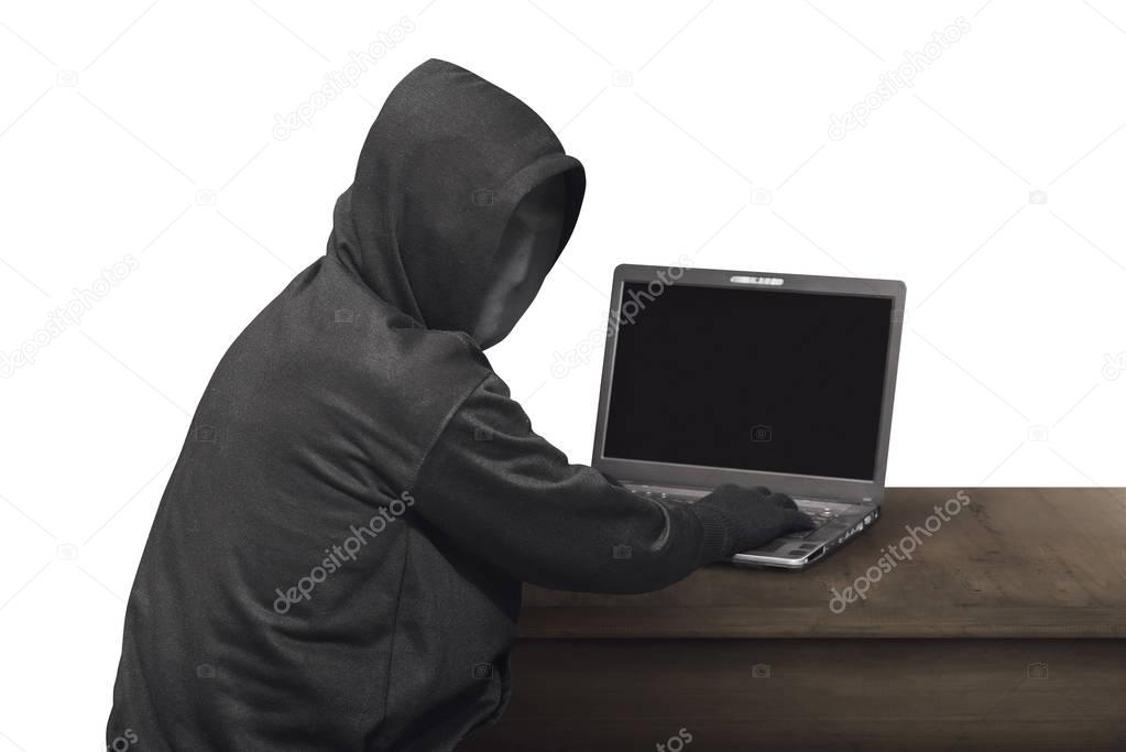 hacker in mask typing on laptop