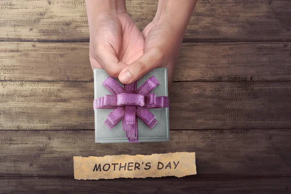 Ręka osób posiadających mały prezent na dzień matki pozdrowienia — Zdjęcie stockowe