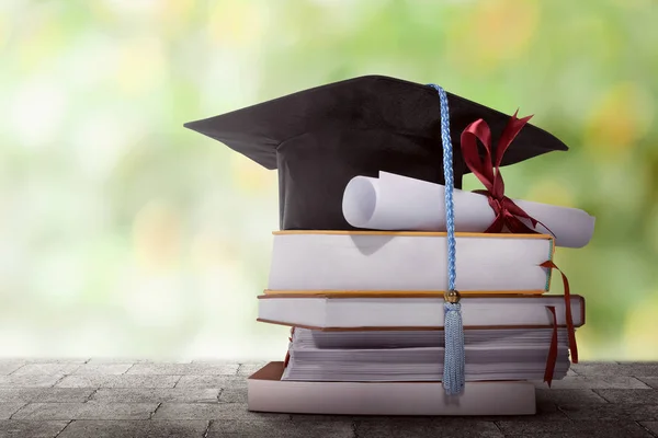 Выпускная шляпа с дипломной бумагой на стопке книг — стоковое фото