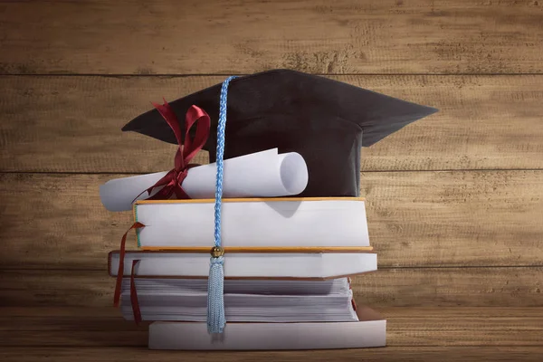 Graduation cap met afstuderen papier op een stapel van boek — Stockfoto