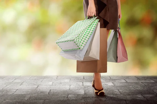 Mujer joven que lleva bolsas de compras multicolores mientras camina —  Fotos de Stock