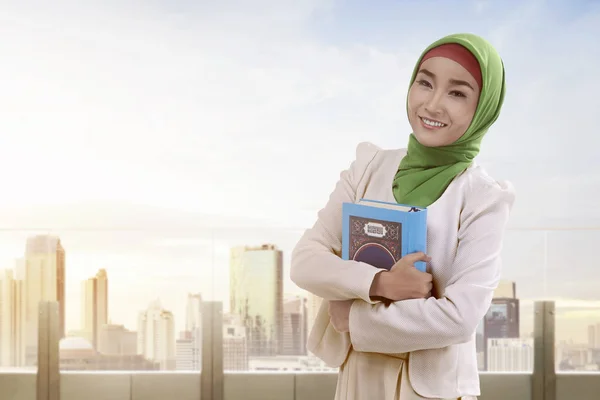 Kvinna med hijab klänning holding Koranen — Stockfoto