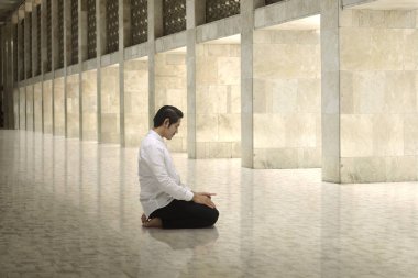 Diz çökmüş ve Tanrı'ya dua yakışıklı Asya Müslüman erkek 