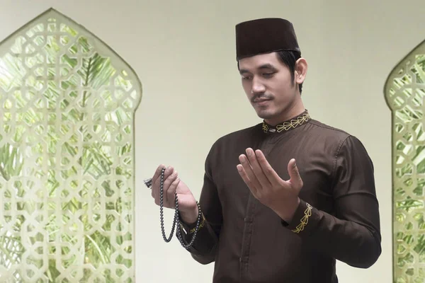 Jeune homme musulman asiatique priant avec des perles de prière — Photo
