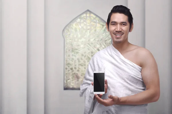 Szép ázsiai férfi a ihram visel ruhát gazdaság mobil p — Stock Fotó