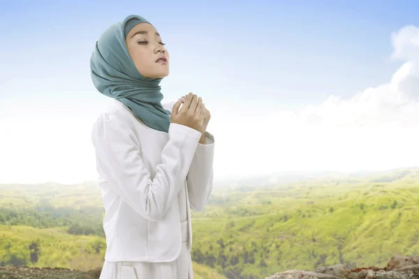 Pretty asian muslim woman wearing hijab raising hand and praying — Stock Photo, Image