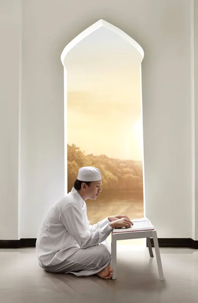 Junger asiatischer muslimischer Mann mit Mütze beim Lesen des Korans — Stockfoto