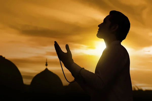 Silhouette of asian muslim man raising hand and praying — Stock Photo, Image