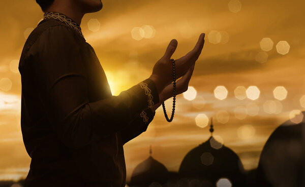 Muslim man raising hand and praying with prayer beads 
