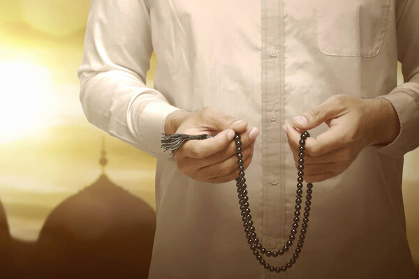 Muslim man holding prayer beads and praying