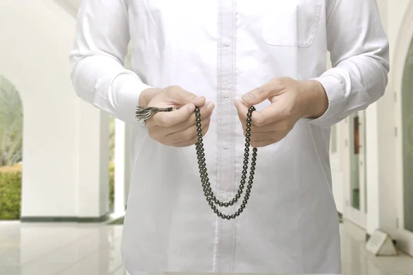 Muslim man raising hand and praying with prayer beads — Stock Photo, Image