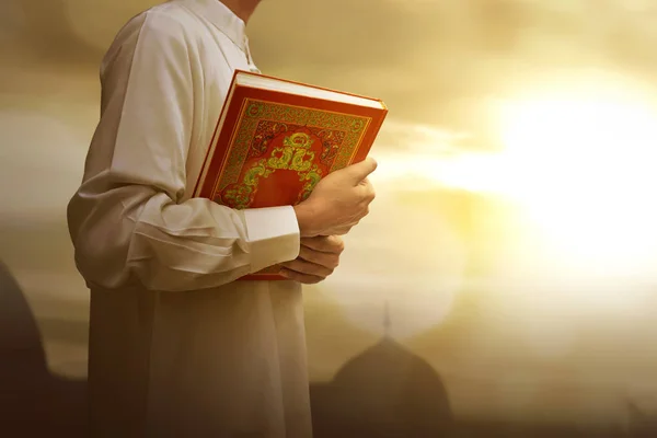 Homme musulman en robe traditionnelle tenant le livre sacré Coran — Photo