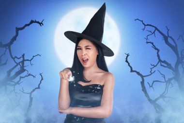 Büyü değnek tutan cadı elbise ile gülümseyen Asyalı kadın