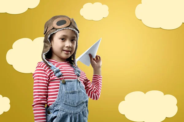 Забавная азиатская маленькая девочка в шлеме летчика, играющая в игрушку для самолета — стоковое фото