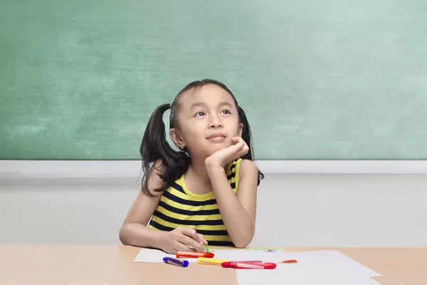 Красивая азиатская маленькая девочка с цветными карандашами рисует на бумаге — стоковое фото