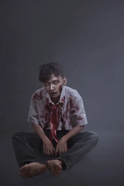 Hemsk asiatiska skrämmande zombie man med sårade ansikte sittande — Stockfoto