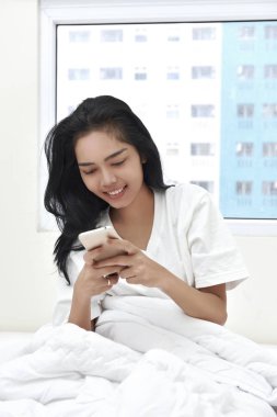 Oturma sırasında cep telefonu tutan genç Asyalı kadın