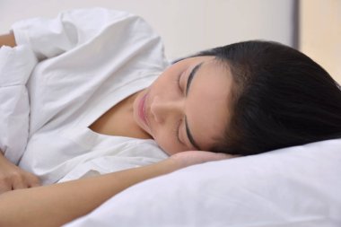 Baş taraftan yalan uyuyan genç Asyalı kadın