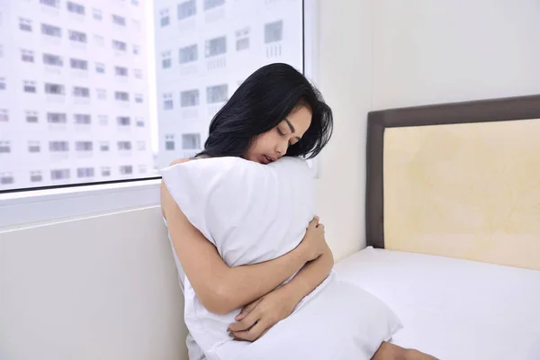 Bela ásia mulher sentado e abraçando branco travesseiro — Fotografia de Stock