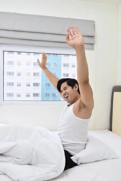 Ung asiatisk man vaknar och sträcker armarna — Stockfoto