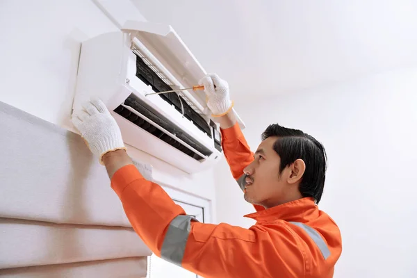 Jonge Aziatische mannelijke technicus reparatie airconditioner met schroef — Stockfoto