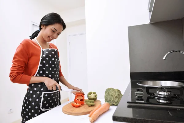 Souriant asiatique femme à l'aide d'un couteau pour trancher les poivrons et la cuisine — Photo