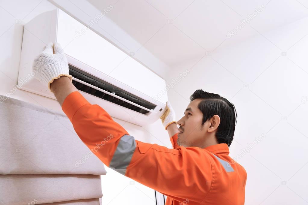 Young asian male technician repairing air conditioner