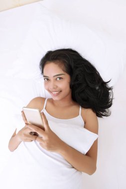 Asyalı kadın Smartphone ile yatarken 