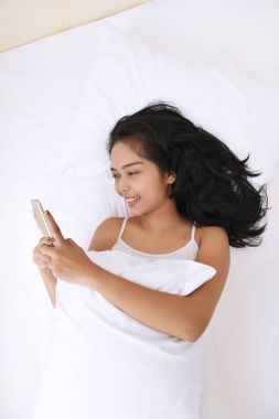 Asyalı kadın Smartphone ile yatarken 