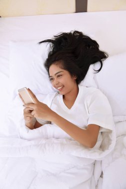 Asyalı kadın Smartphone ile yatarken 