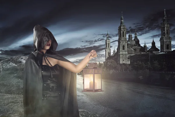 Young asian witch with black cloak holding lantern — Stock Photo, Image