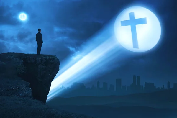Man looking bright cross on the edge of cliff — Stock Photo, Image