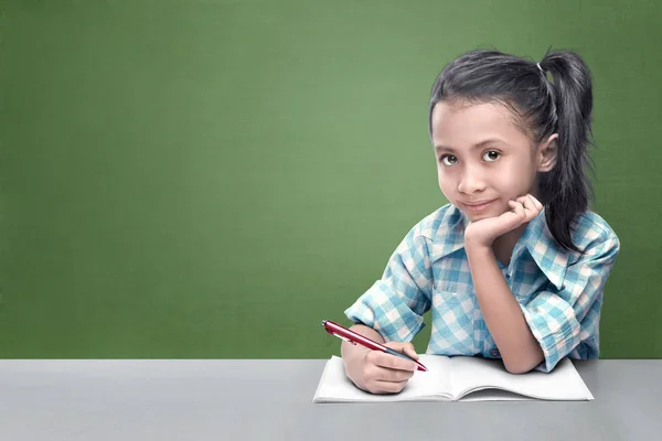 黒板背景に彼女の宿題をしているアジアの少女の笑顔 — ストック写真