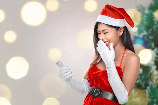 Aufgeregte Asiatin Weihnachtskleidung Mit Handy Vor Verschwommenem Hintergrund — Stockfoto