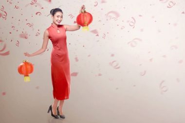 Çince fener tutarak cheongsam elbise giyen genç Çinli kadın. Mutlu Çin yeni yılı