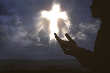 Eller yükselterek ve tepe üzerinde Tanrı'ya dua adam silüeti