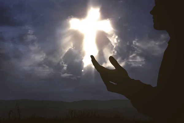 Eller yükselterek ve tepe üzerinde Tanrı'ya dua adam silüeti