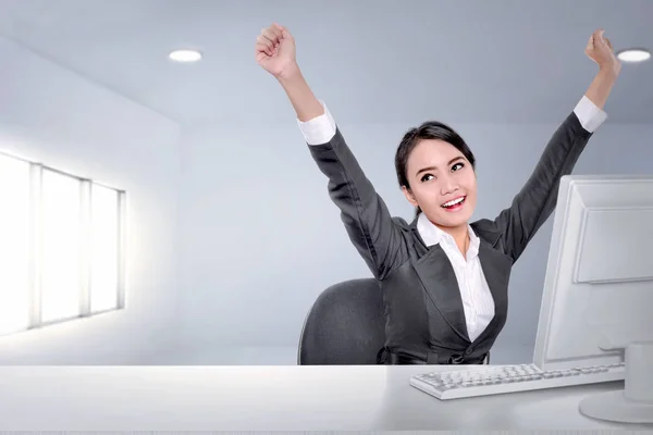 Excited asian business woman with arms up while working