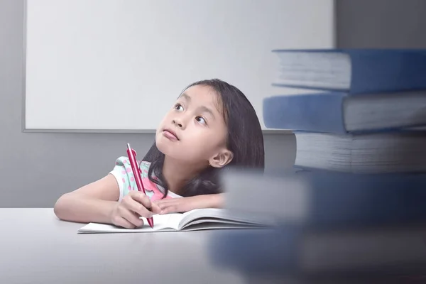 Feliz asiática niña pensando con libro y pluma — Foto de Stock