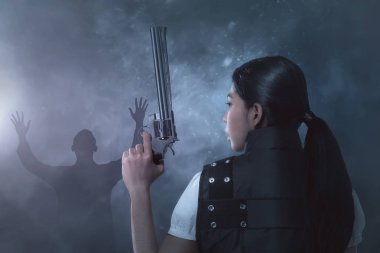Bir polis üniforması ona tabanca ile genç Asyalı kadın koyu arka plan üzerinde eller