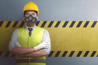 Genç Asyalı inşaat işçisi ile çapraz kol ayakta duvara çizgili sarı karşı