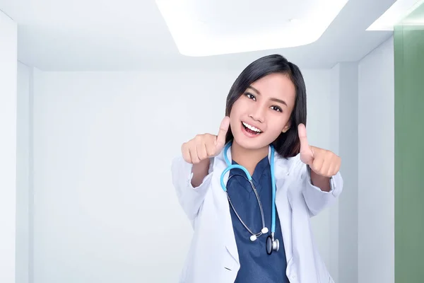 クリニック ルームで親指に現れる白いコートで美しいアジア女性医師 — ストック写真