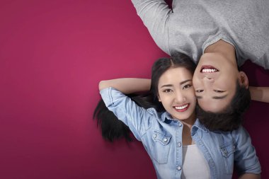 Pembe arka plan üzerinde yatarken ararken romantik Asya çift