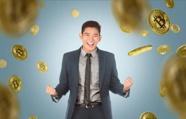青の背景に Bitcoin 雨の下でスーツで魅力的なアジア系のビジネスマン — ストック写真