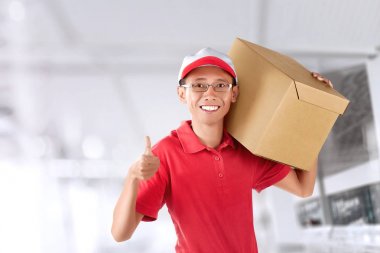 Kırmızı üniforma başparmak gösterilmesini ve teslim kapalı, parsel Asya kurye adamla gülümseyen