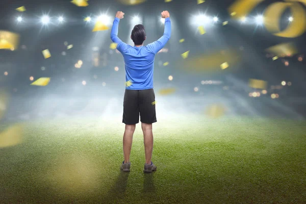 Back view of asian man celebrating victory with confetti background