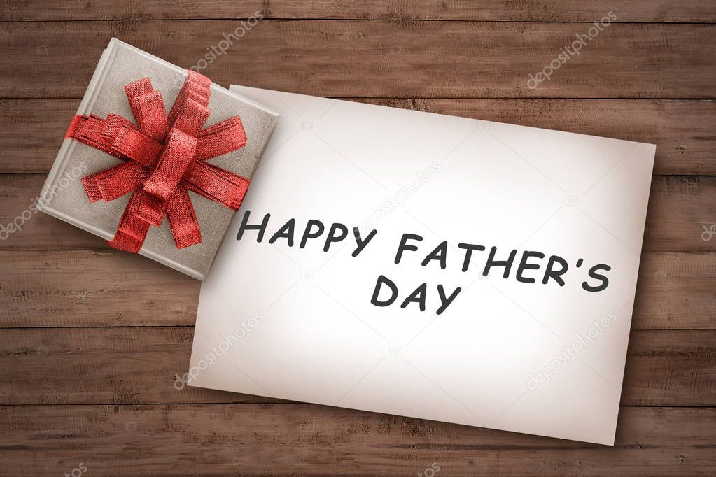 Happy fathers day messages on paper with gift on wooden background