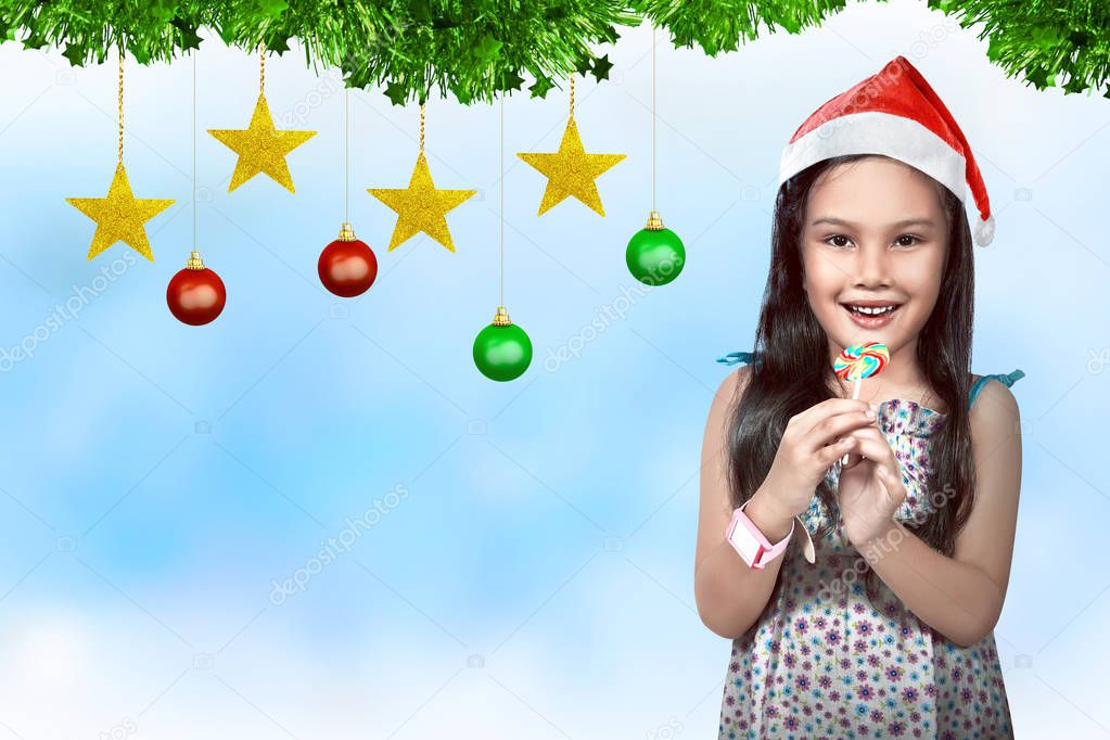 Cute asian little girl wearing santa hat with christmas decoration on background. Christmas in July